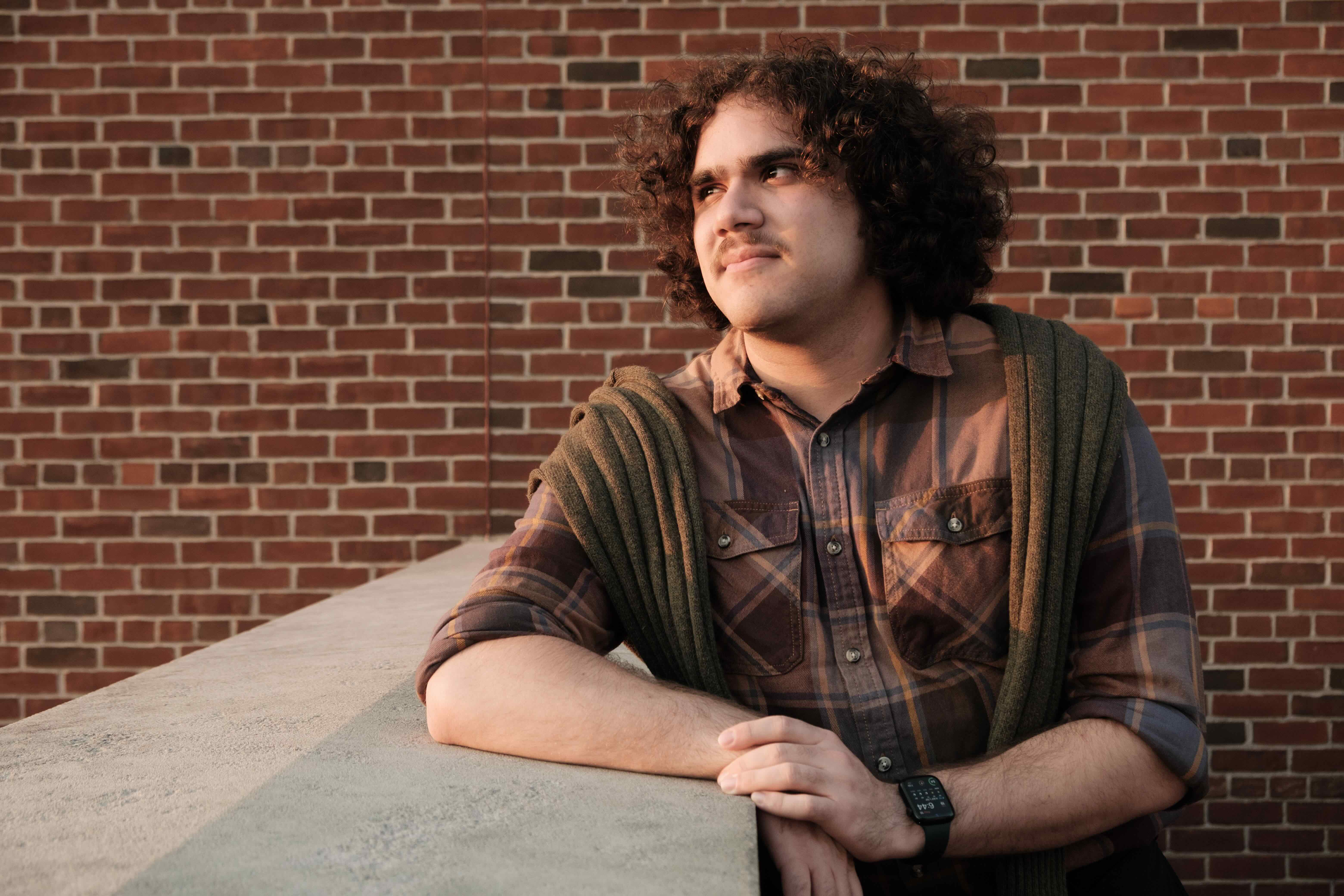 Caleb looking over to his left in front of a brick wall